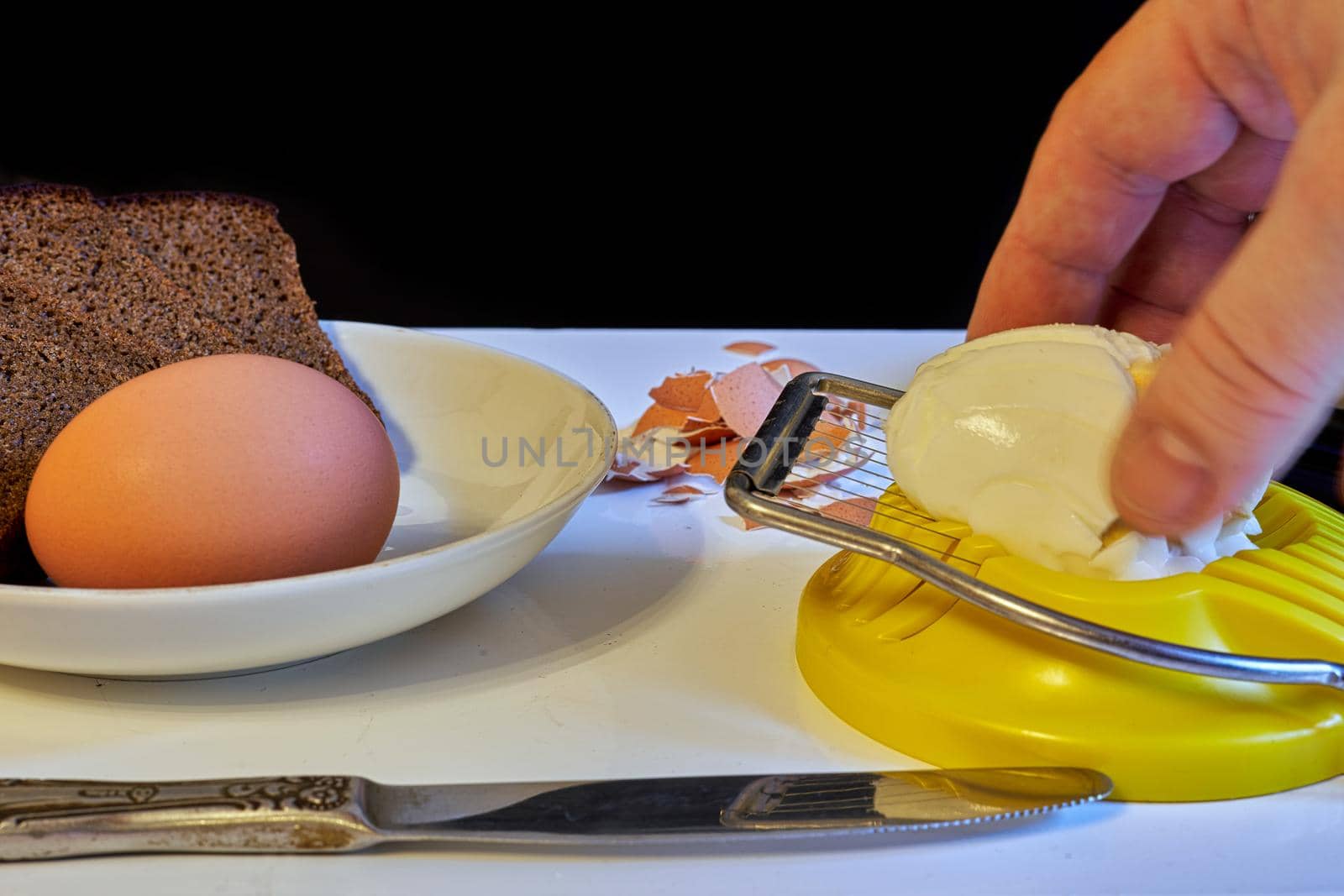 Hand controls an egg cutter on the background of products for making a sandwich, preparing food for breakfast, close up