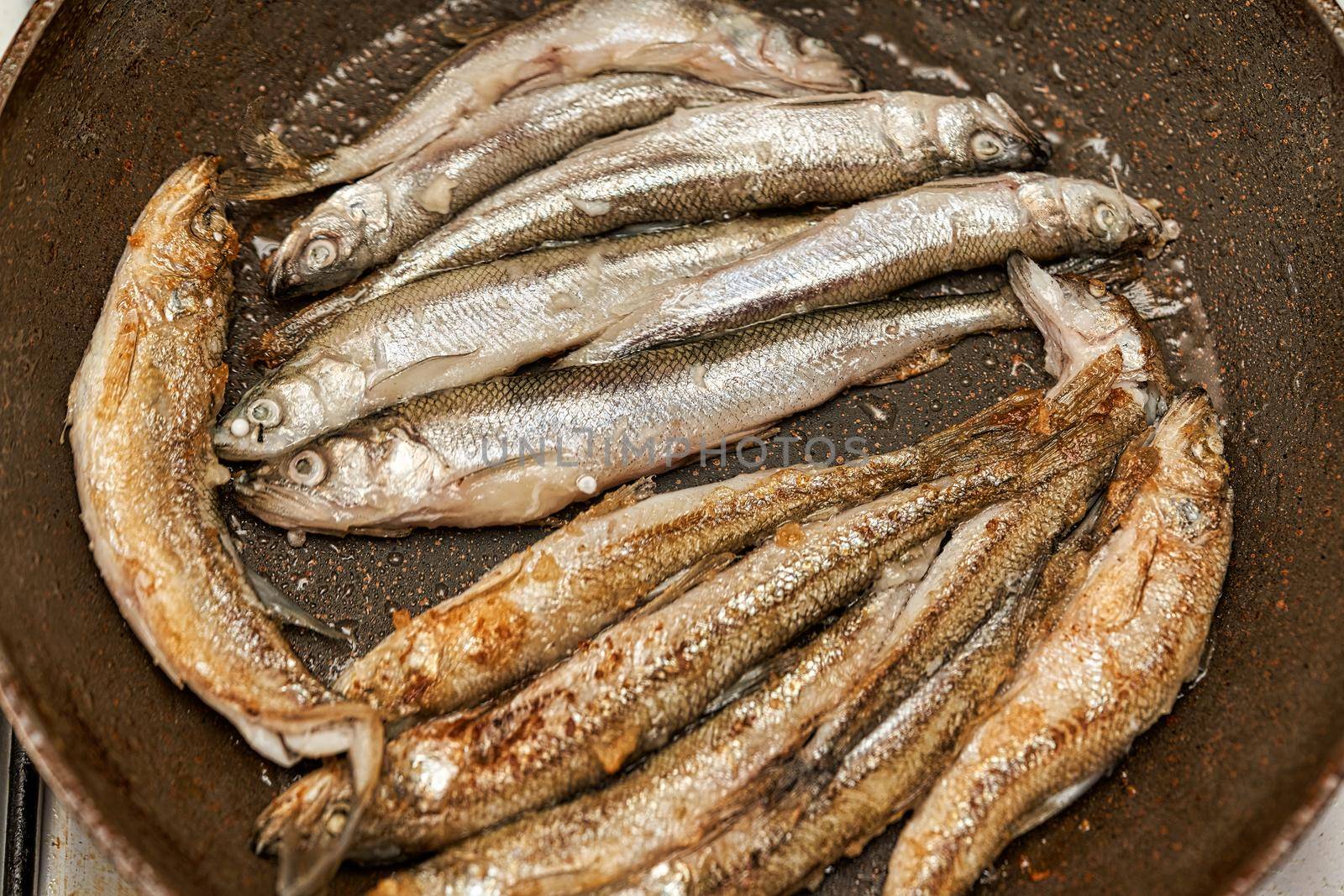 Fresh raw silver fish smelt fried in a skillet. Close up