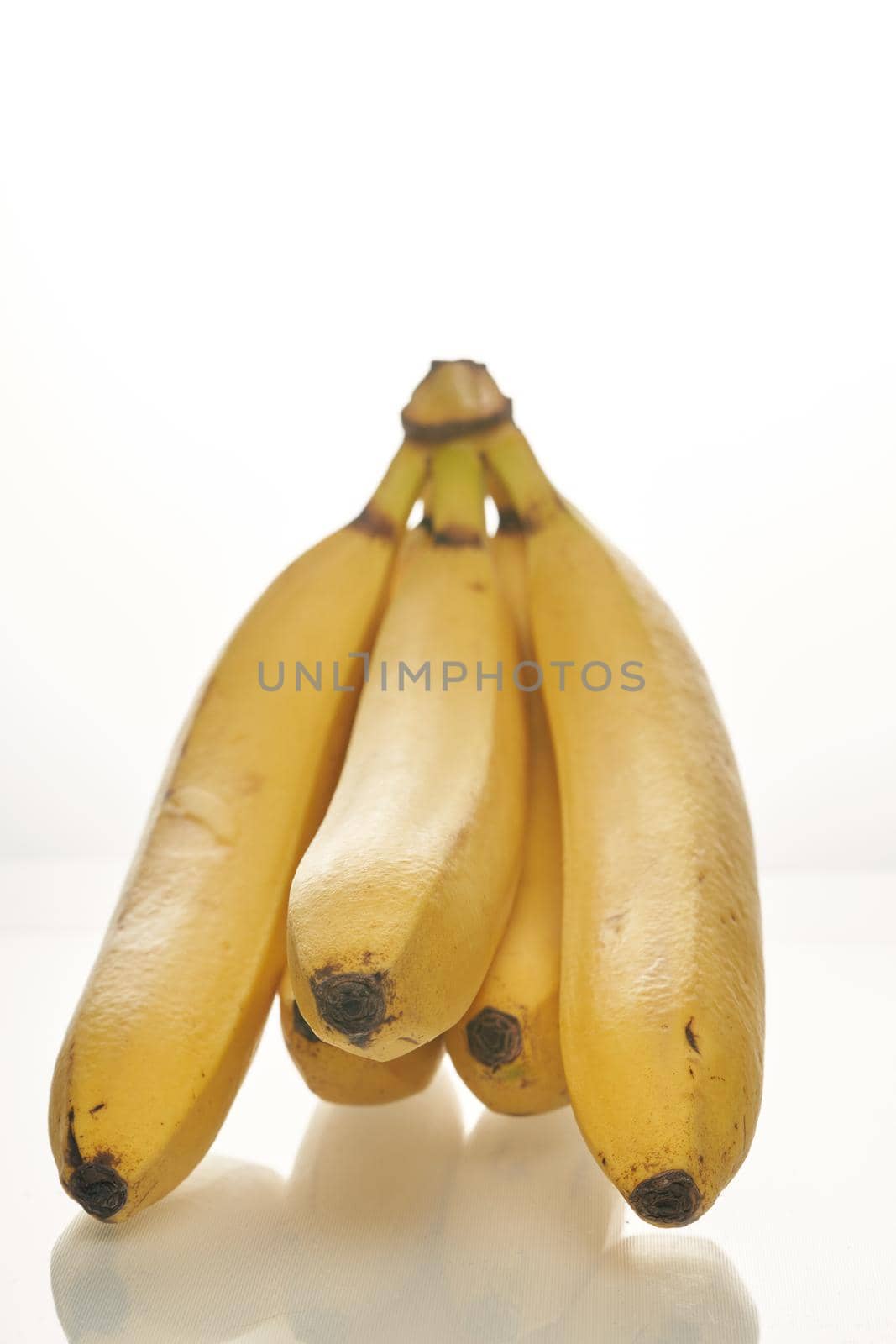 Bunch of ripe yellow bananas on white background. Close up, vertical shot