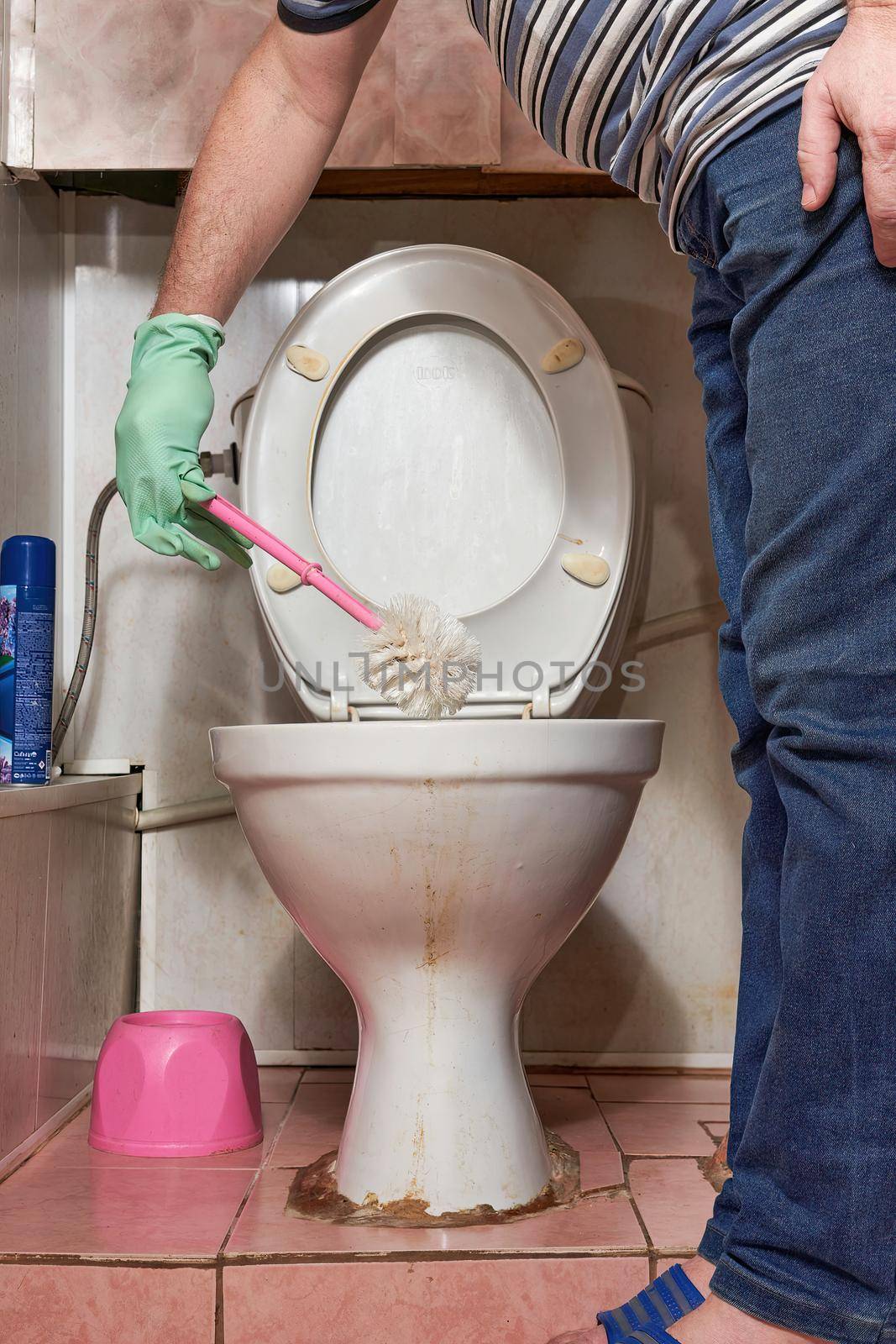 Hand with toilet brush cleans old dirty toilet bowl. Cleaning the toilet with household gloves