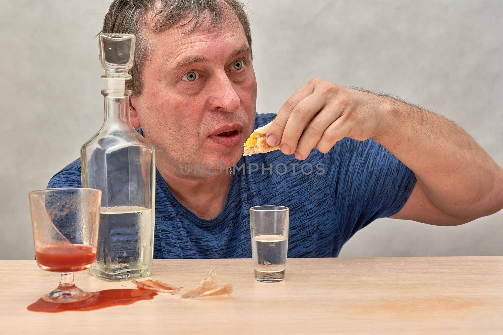 A drunkard sitting at a table seizes alcohol alone. Household alcoholism problems