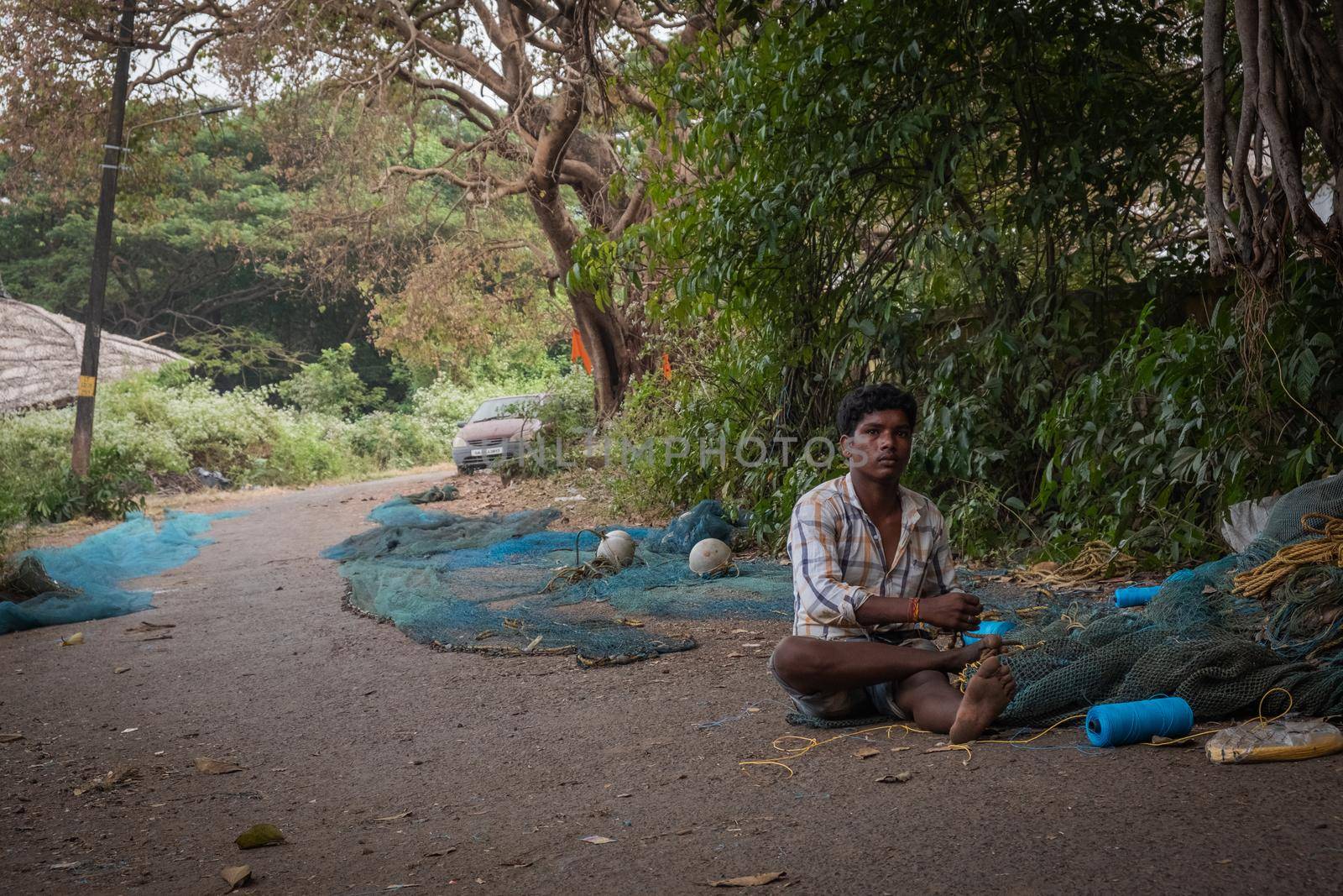 Indian Fisherman repairs fishing net in Goa, India