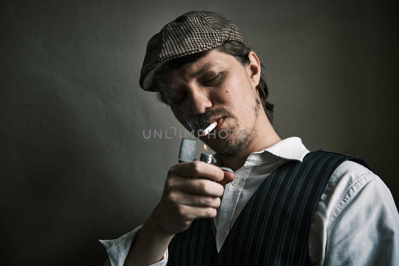 Young guy lights a cigarette, blows smoke, dressed in a retro style, in a beret, cinematic shot, big closeup