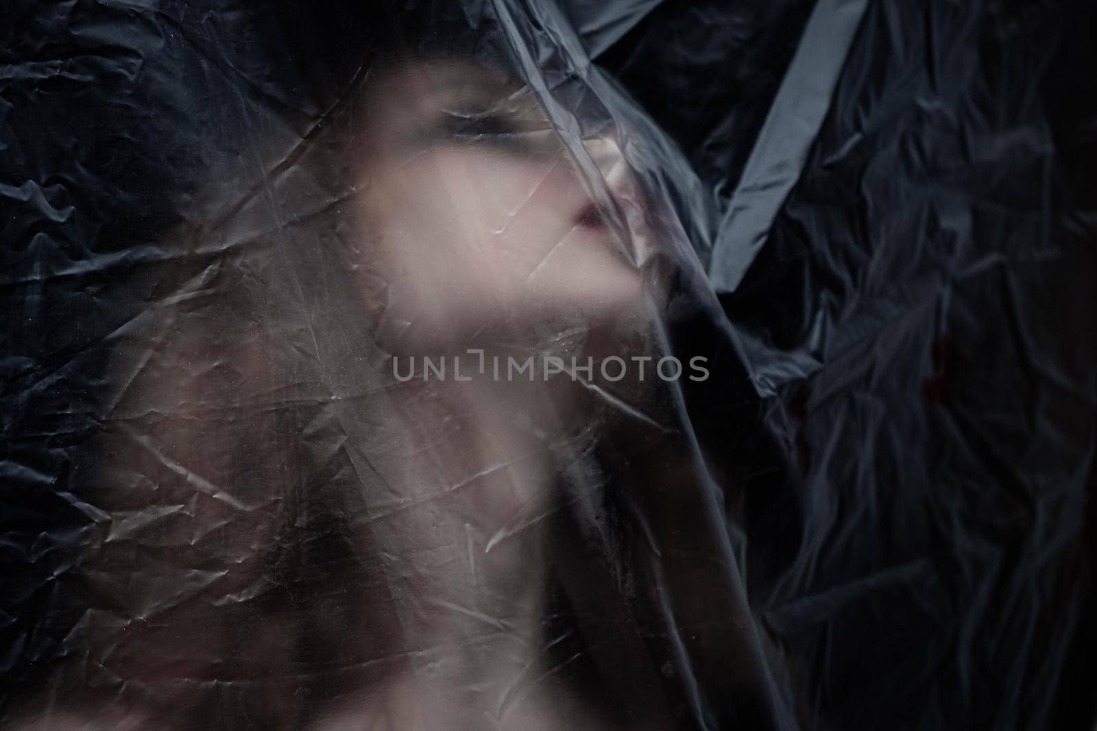 Young beauty sad woman trapped behind a plastic sheet as protection against COVID-19. Nicely fits for book cover by snep_photo