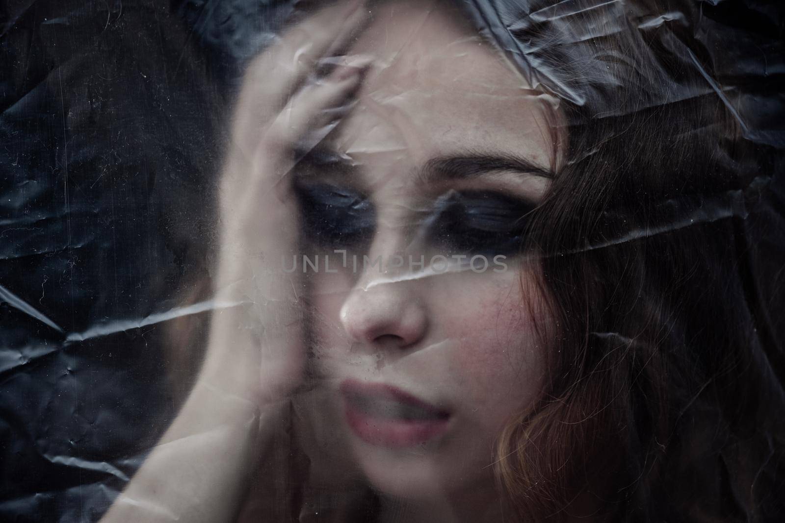 Young beauty sad woman trapped behind a plastic sheet as protection against COVID-19. Nicely fits for book cover by snep_photo