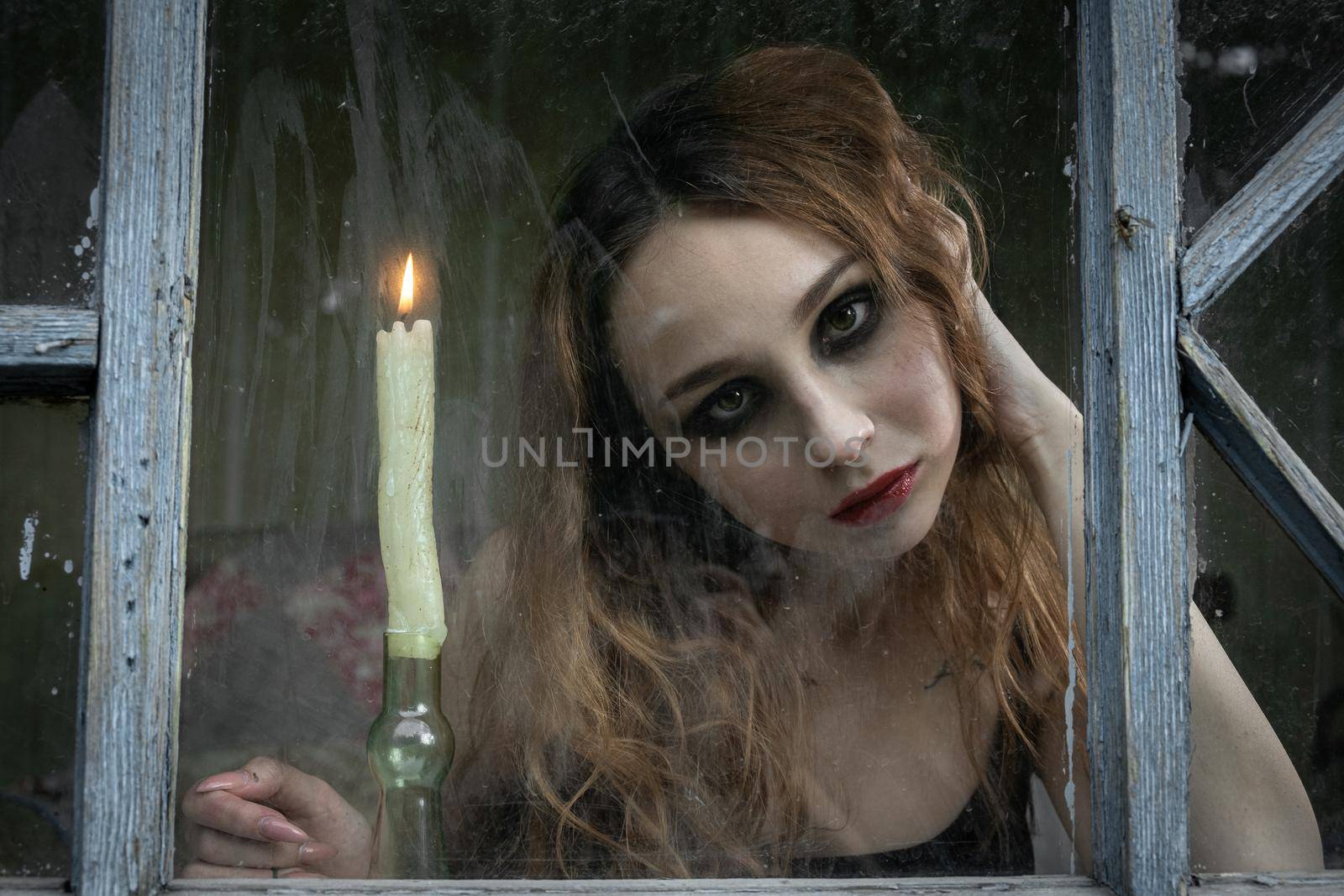 Beautiful sad young girl looking out the window with a candle by snep_photo