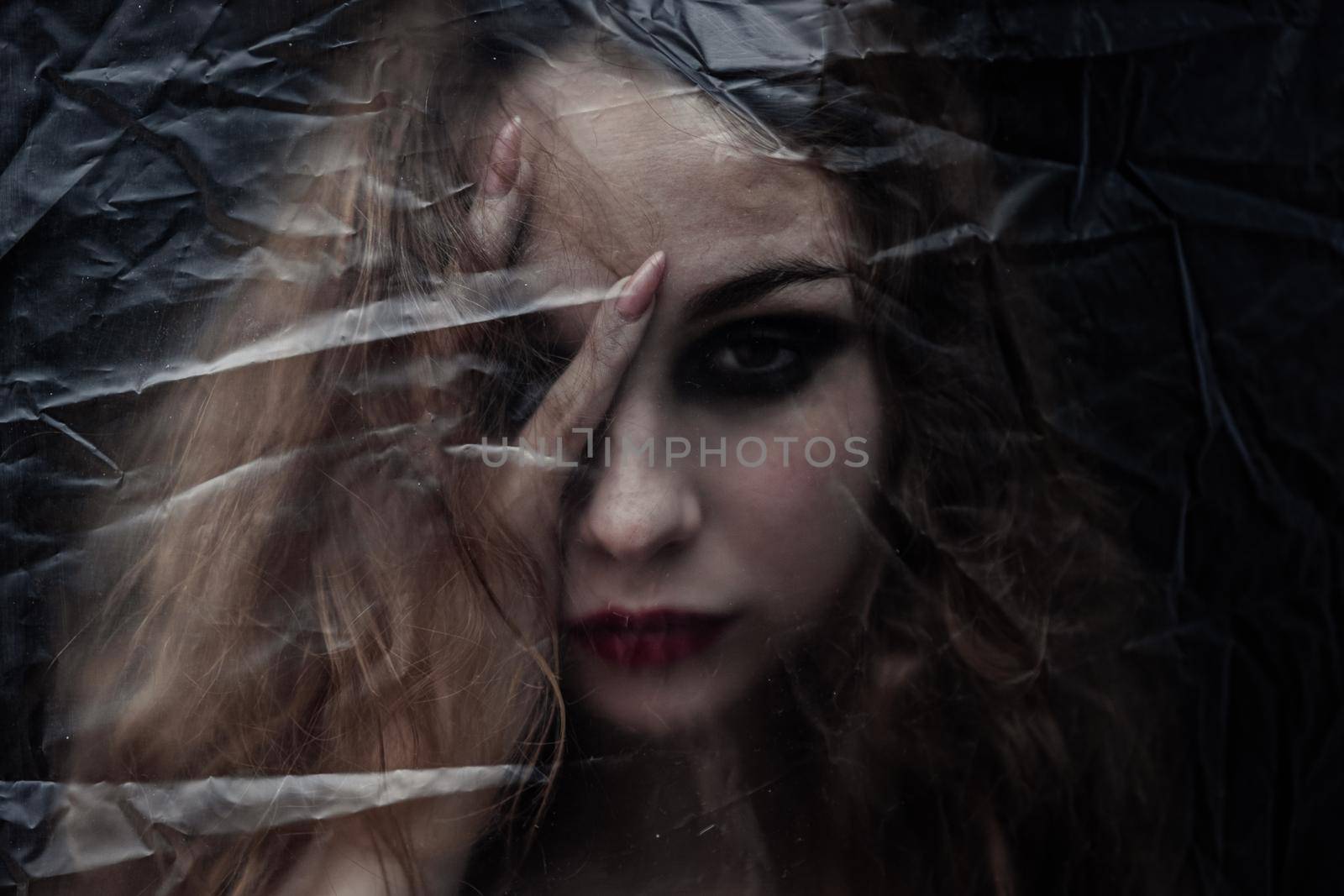 Young beauty sad woman trapped behind a plastic sheet as protection against COVID-19. Nicely fits for book cover