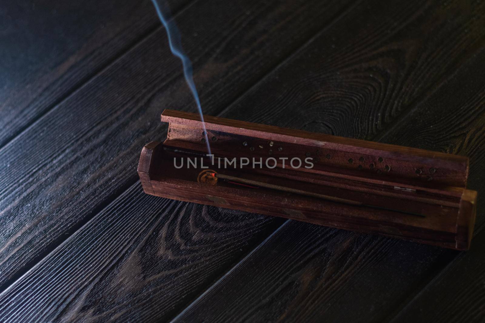 Focus on incense stick and smoke in a wooden stand. Symbol Japanese culture