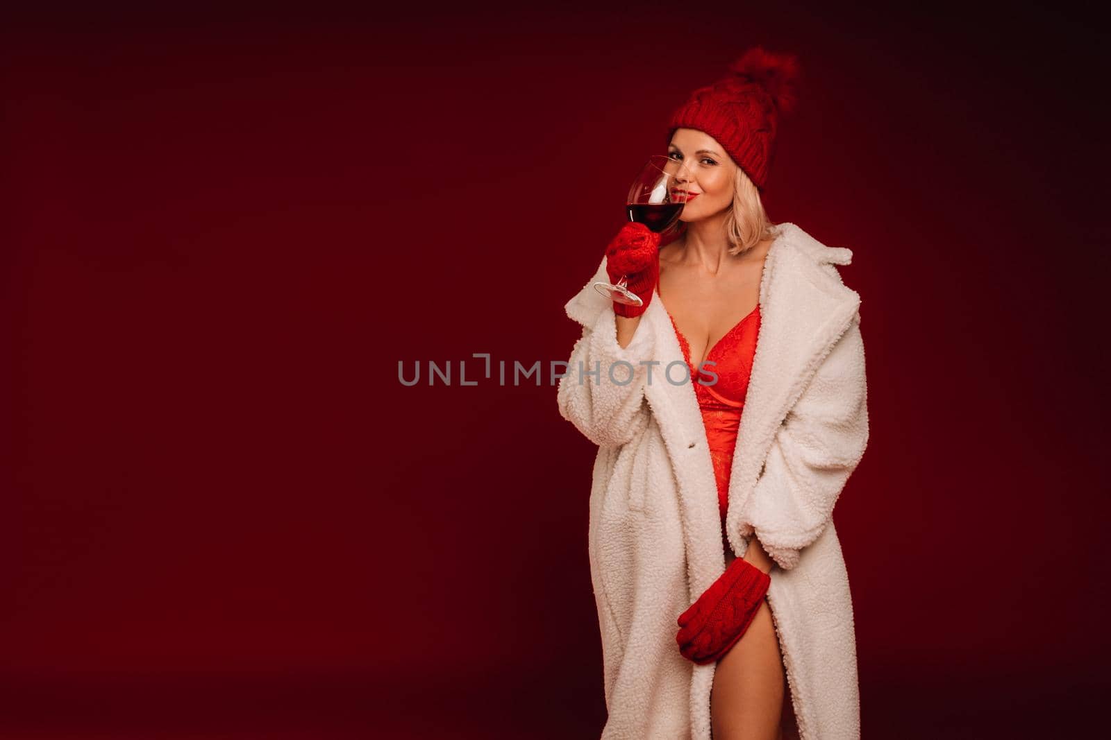 portrait of a smiling girl in a white fur coat and underwear holding a glass of champagne on a red background by Lobachad