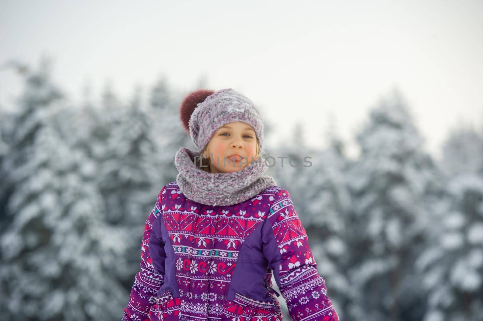 a little girl in winter in purple clothes walks through a snow-covered forest.