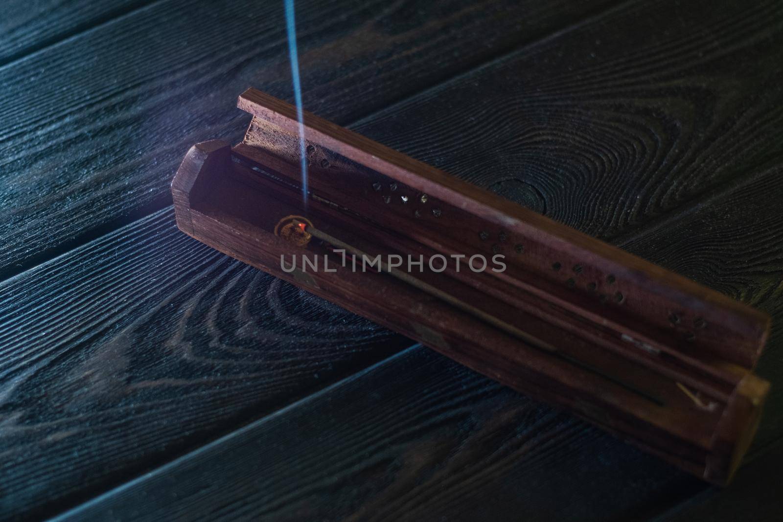 Focus on incense stick and smoke in a wooden stand. Symbol Japanese culture