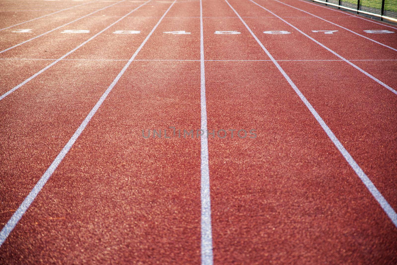 Athletic track in natural light with long numbered lanes to the horizon gives the feeling of preparedness focus and direction, with no people, and copy space