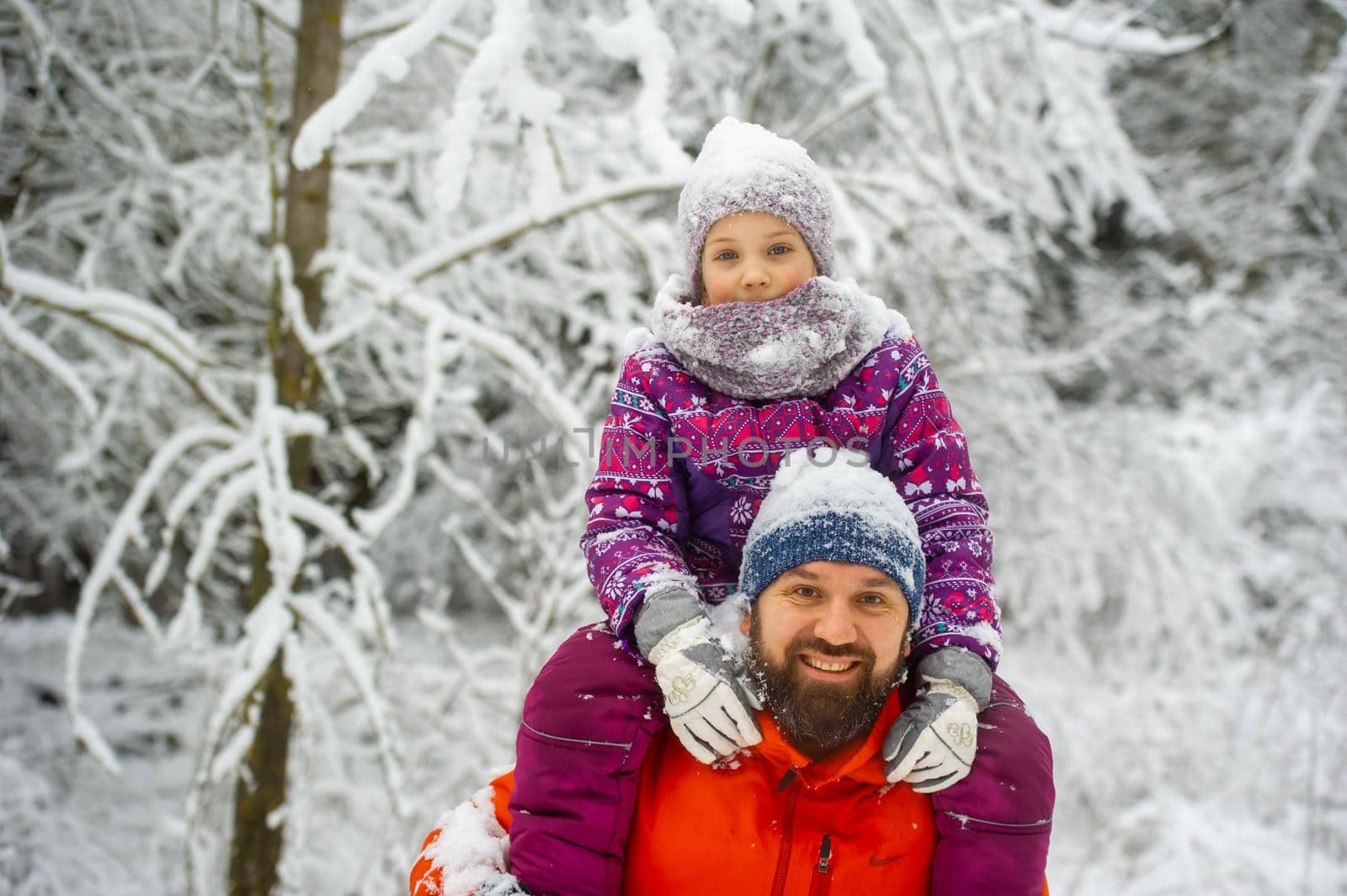 Family dad and daughter walk in the snow-covered forest in winter.