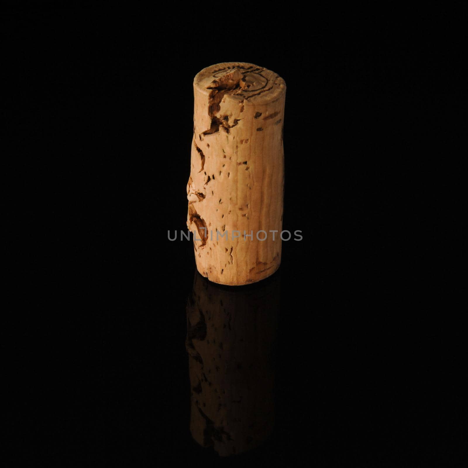 One old wine cork on black background with reflection