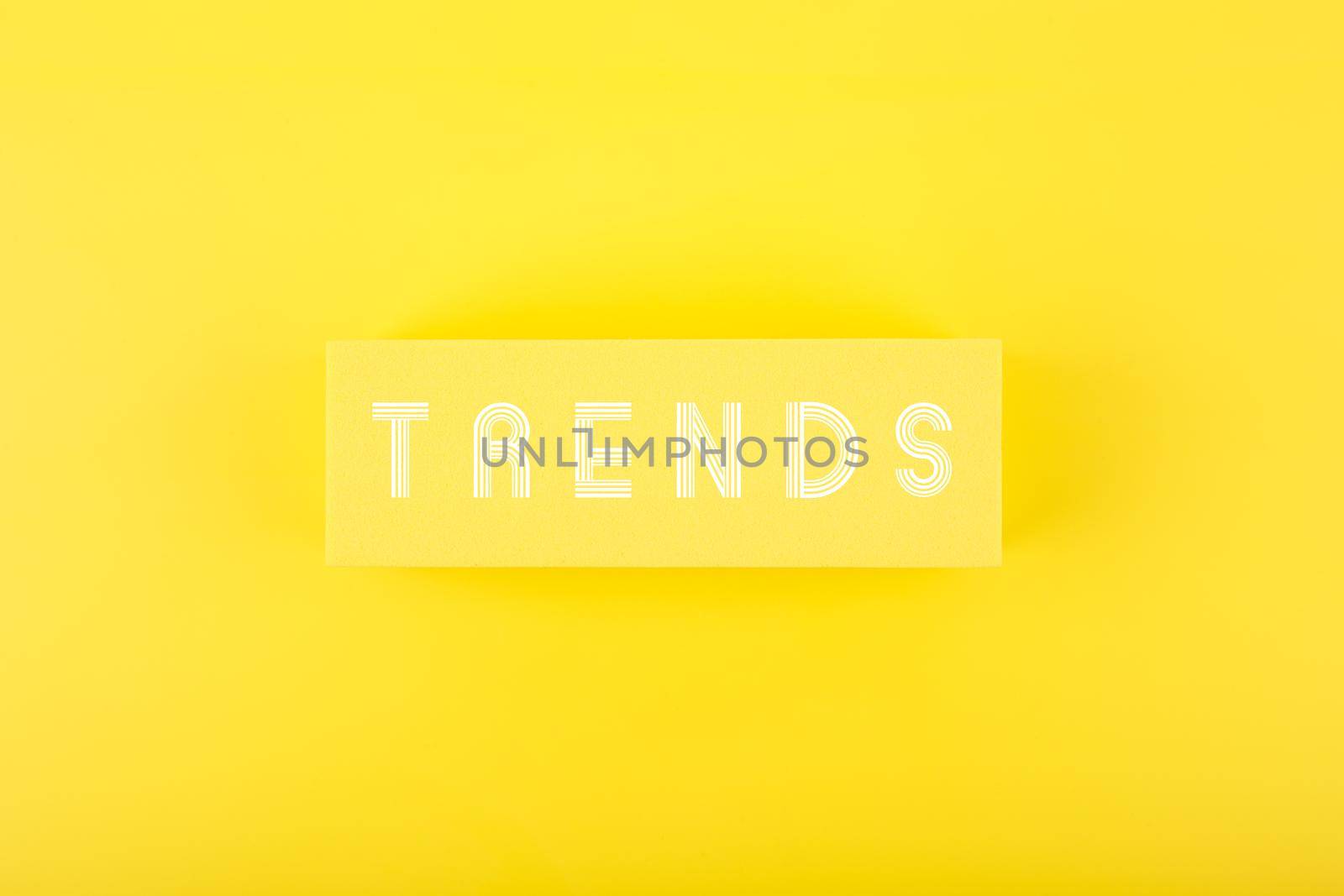 Minimal flat lay with word Trends written on rectangle on bright yellow background. Concept of newest, latest, hot and popular trends 