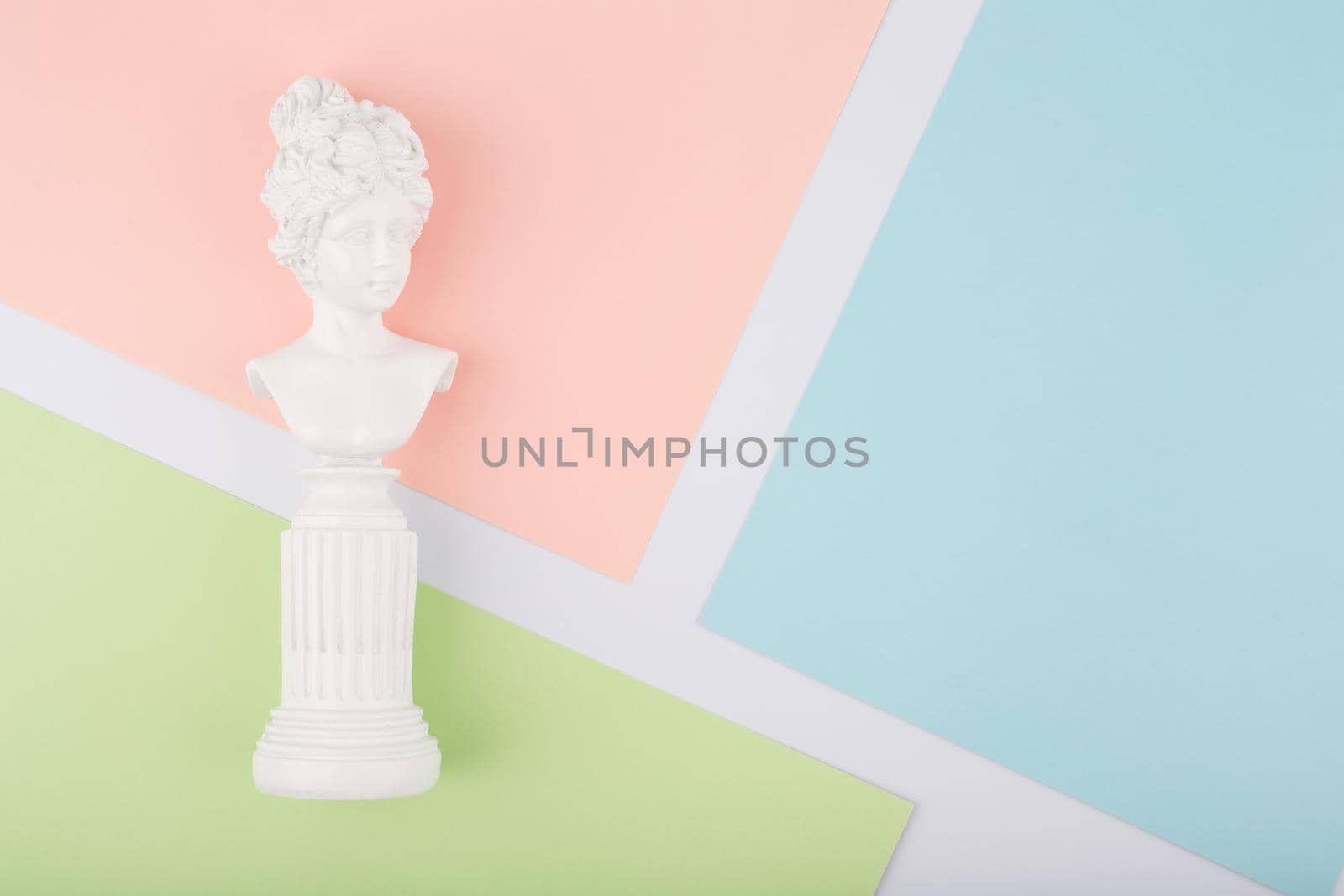 White gypsum classic woman figure on bright multicolored background with copy space. Antique female statue on colorful paper