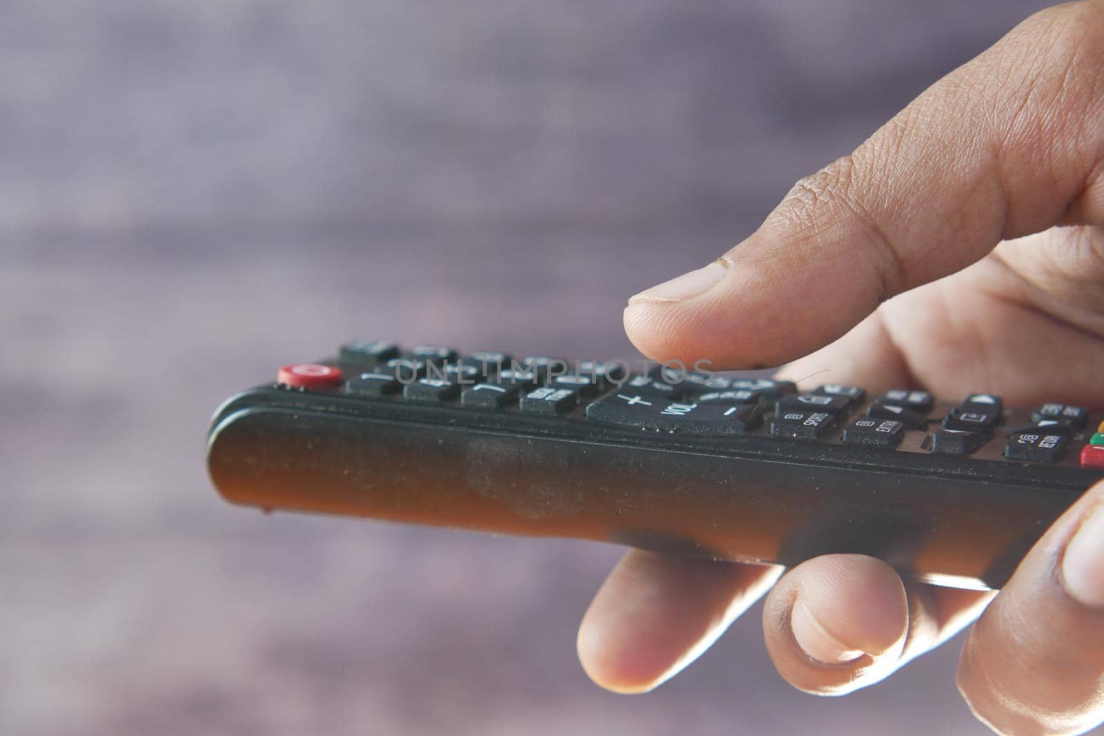 close up of man hand holding tv remote