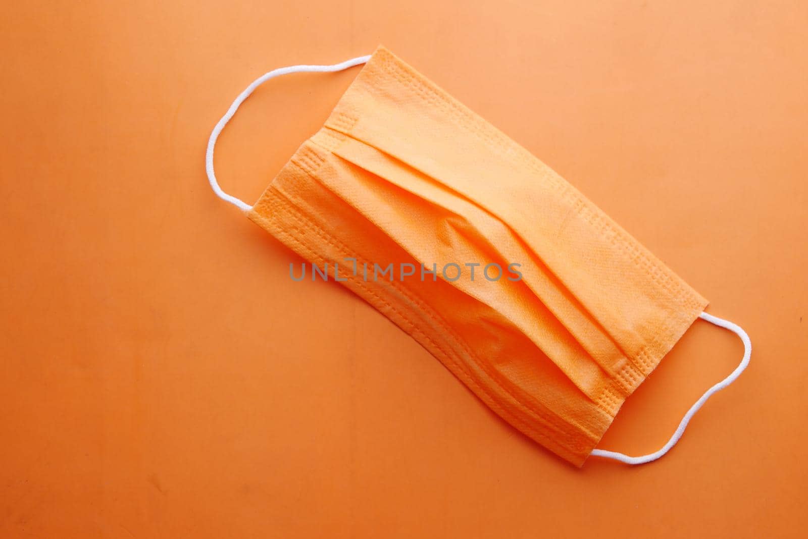 Close up of orange color surgical masks on color background ,