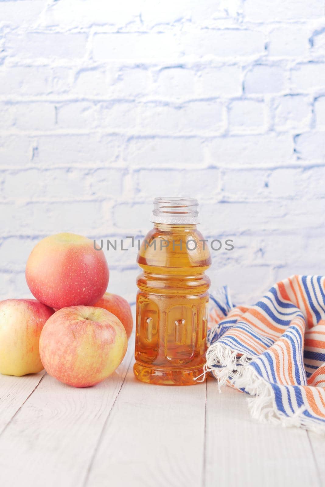 fresh apples and bottle of juice on table .