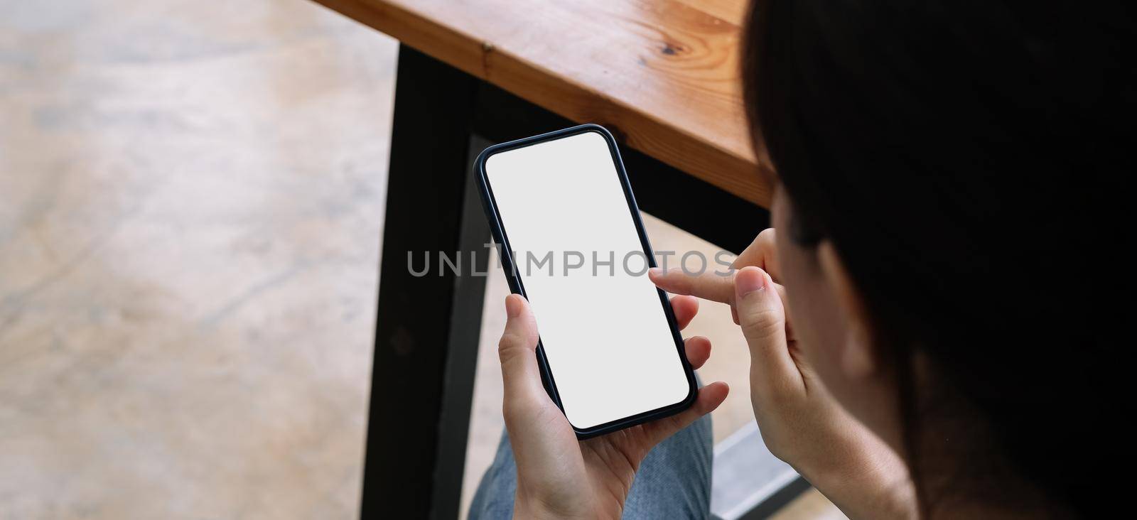 Woman sitting and holding blank screen mock up mobile phone
