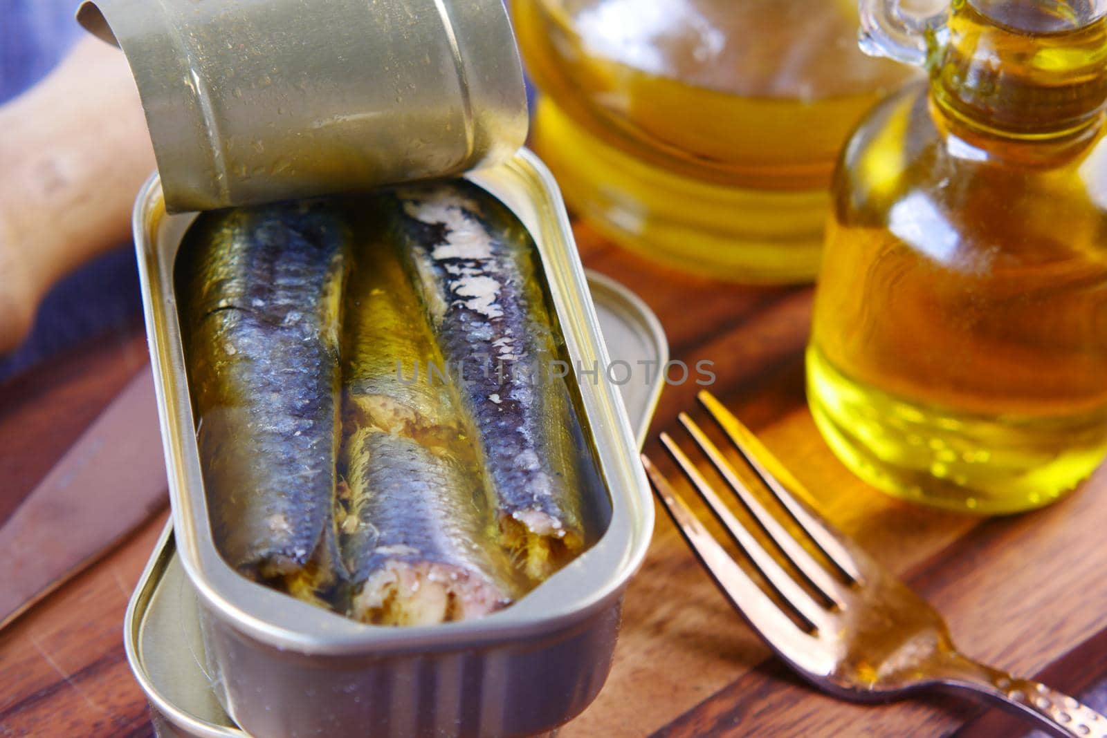 open tin of sardines and olive oil on table ,