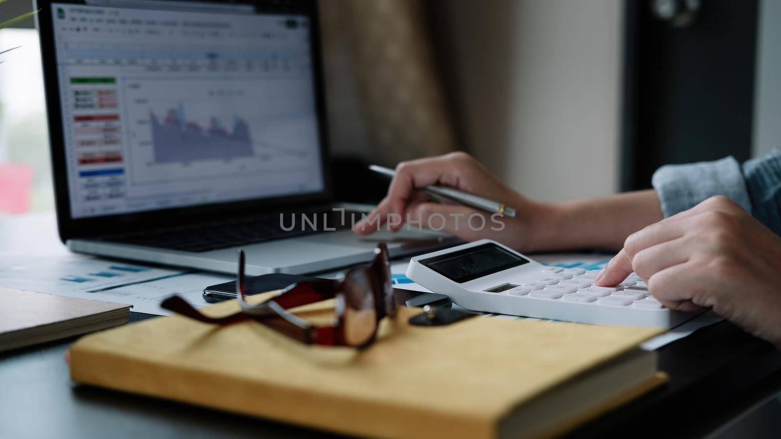 Close up hand woman doing finance and calculate with calculator on desk about cost , work from home concept.