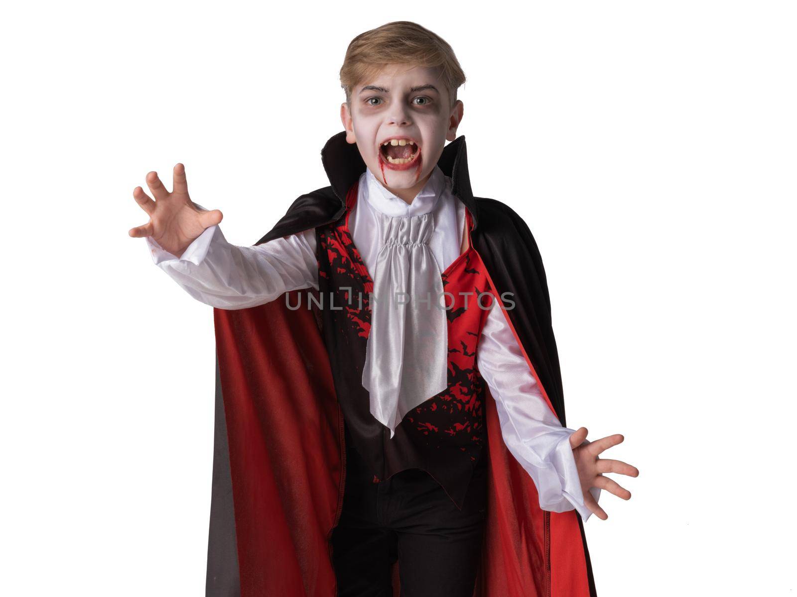 Portrait of boy wearing Halloween vampire makeup and costume cloak bare his teeth, isolated on white background.
