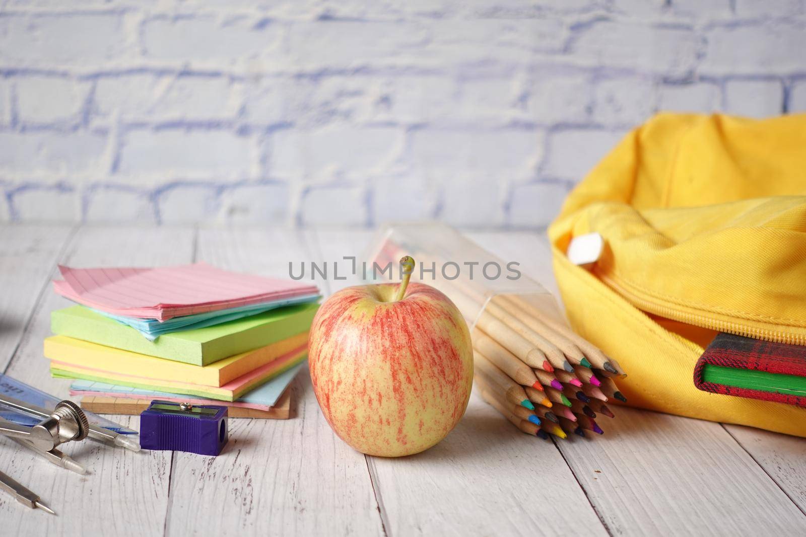 back to school concept with yellow backpack and school suppliers on table.