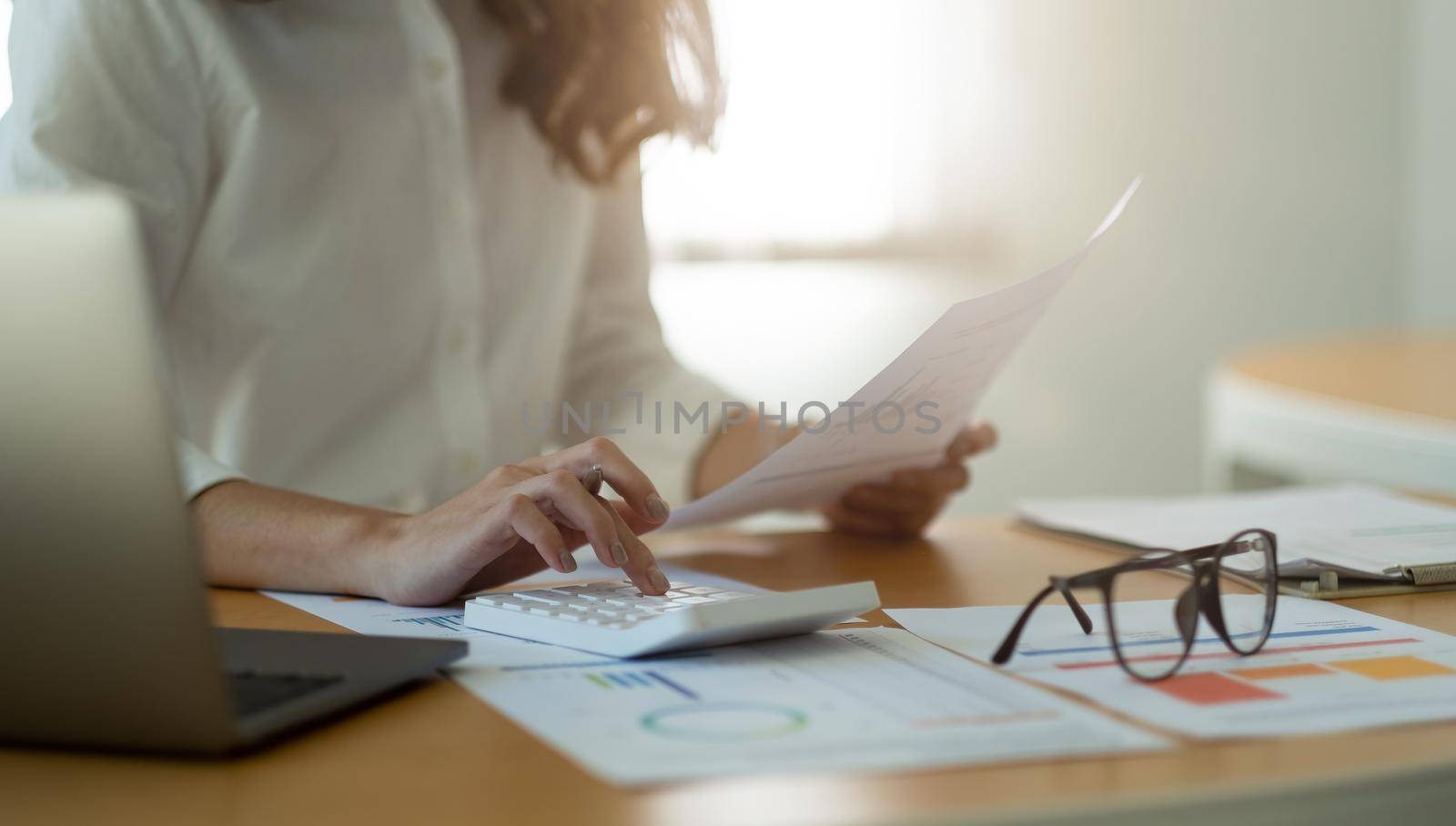 Businesswoman or accountant working Manager Researching Process accounting calculate with calculator for analyse market graph data stock information review on the table in office