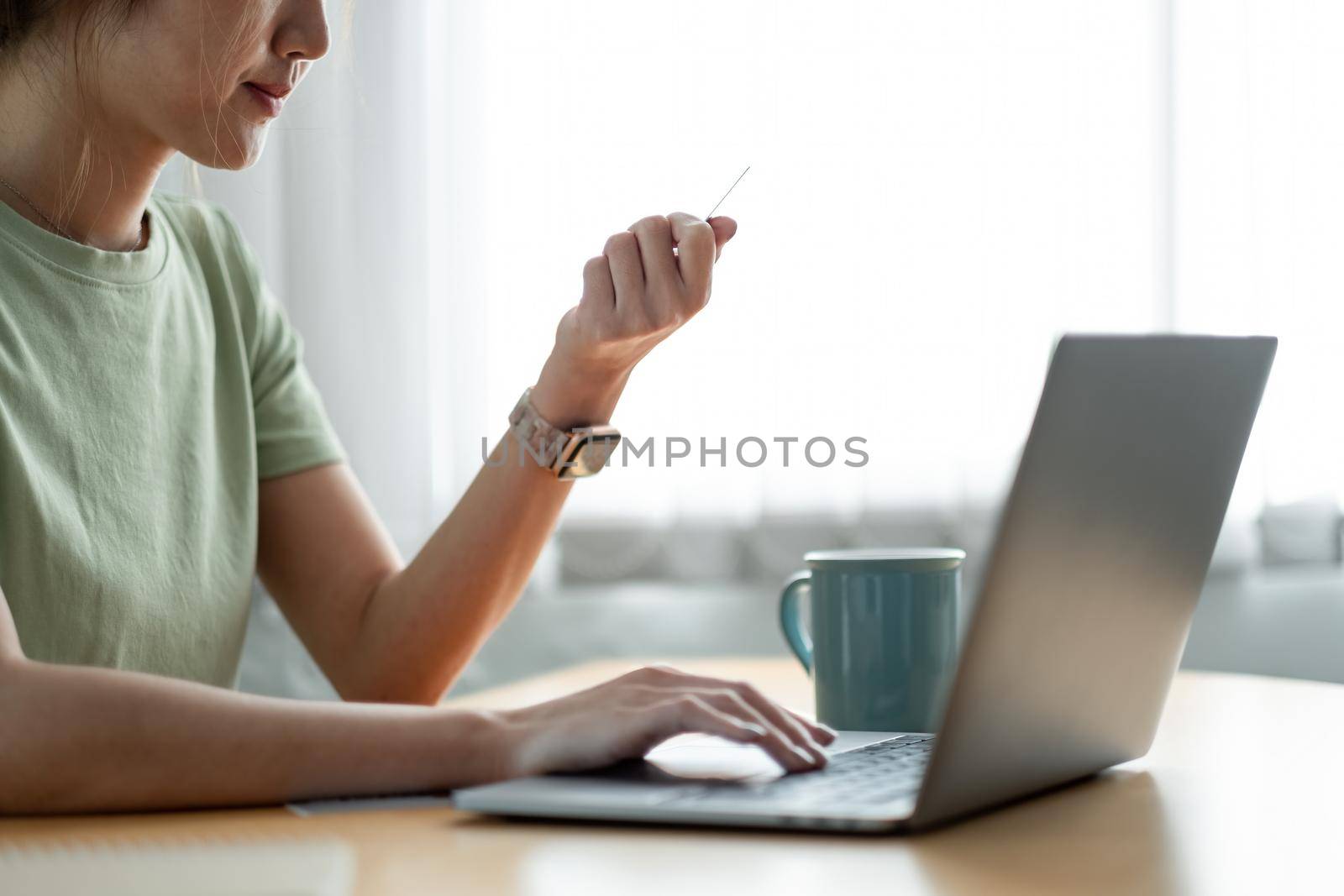 Close-up woman hands holding a credit card and using computer keyboard for online shopping at home.