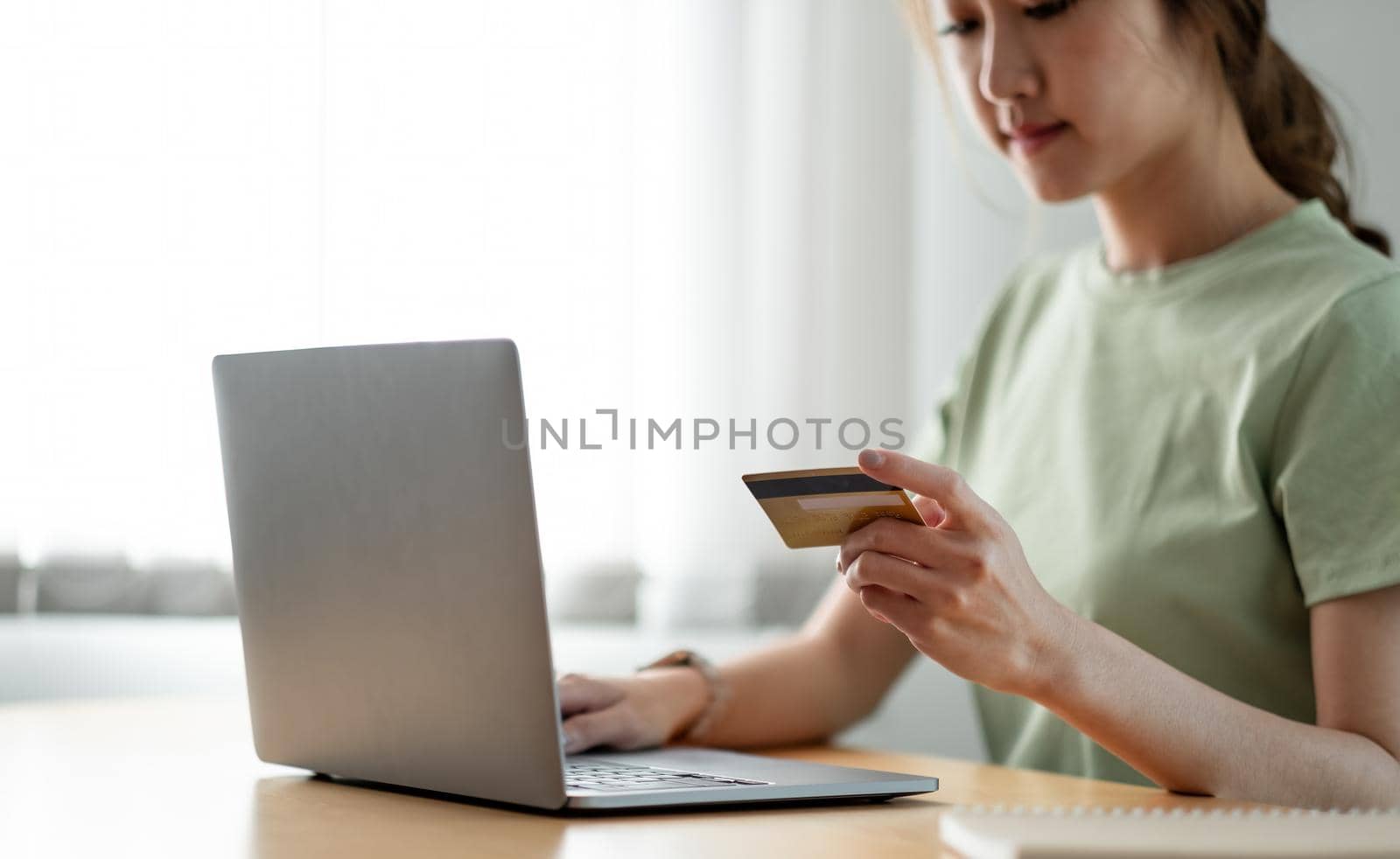 Happy woman doing online shopping at home, woman hand holding credit card and using laptop computer.