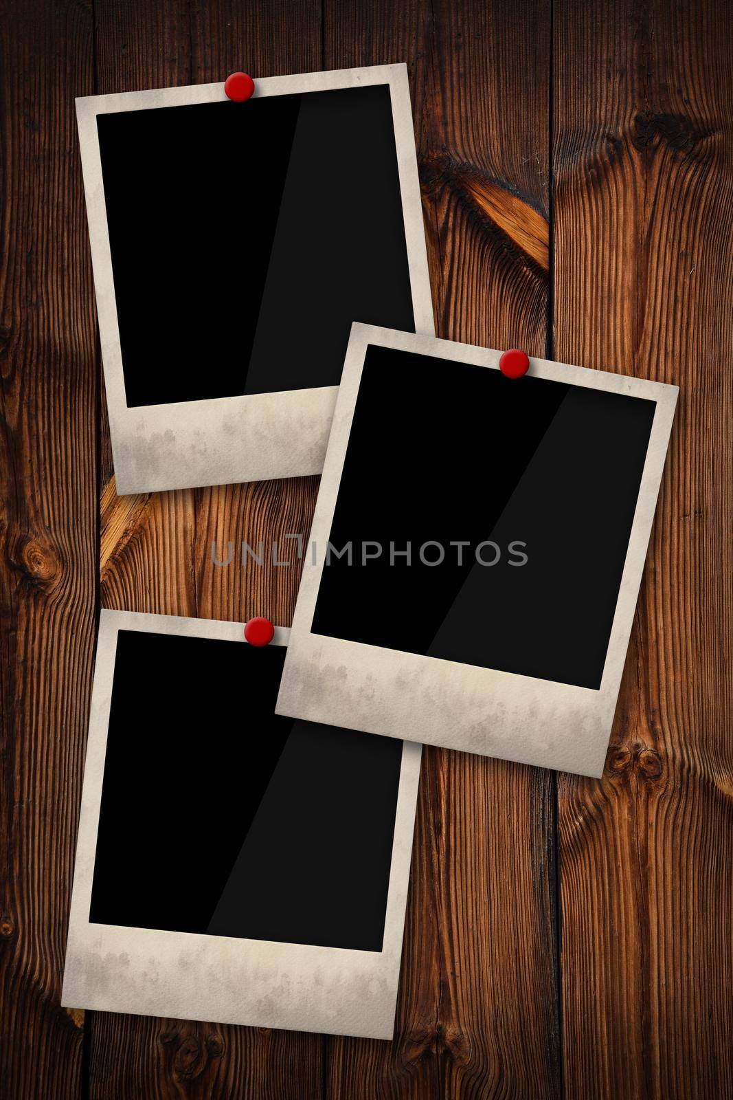 Close up three empty Polaroid instant photo frames pinned on old grunge brown wooden wall background, low angle, side view