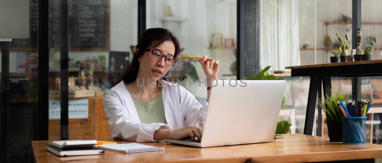 Cropped photo of woman writing making list taking notes in notepad working or learning on laptop indoors- educational course or training, seminar, education online concept.