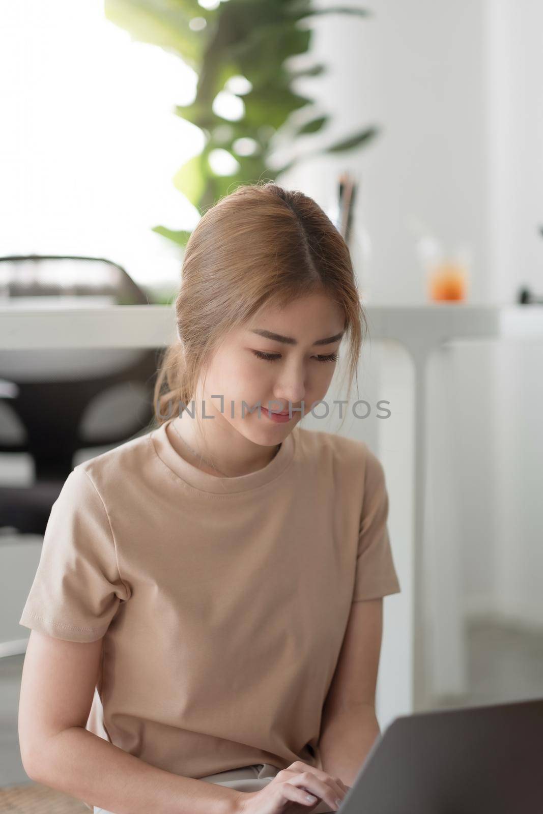 Portrait charming asian woman sitting on the floor working on laptop at home.