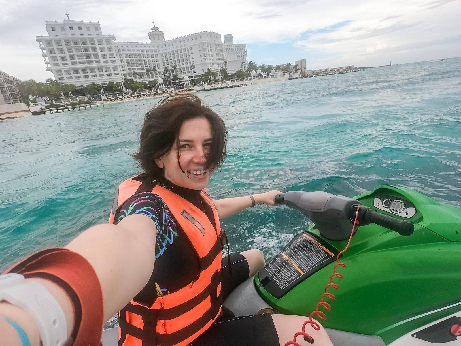 Woman making selfie photo while riding jet ski on Caribbean sea resort. Concept of having fun on summer vacation