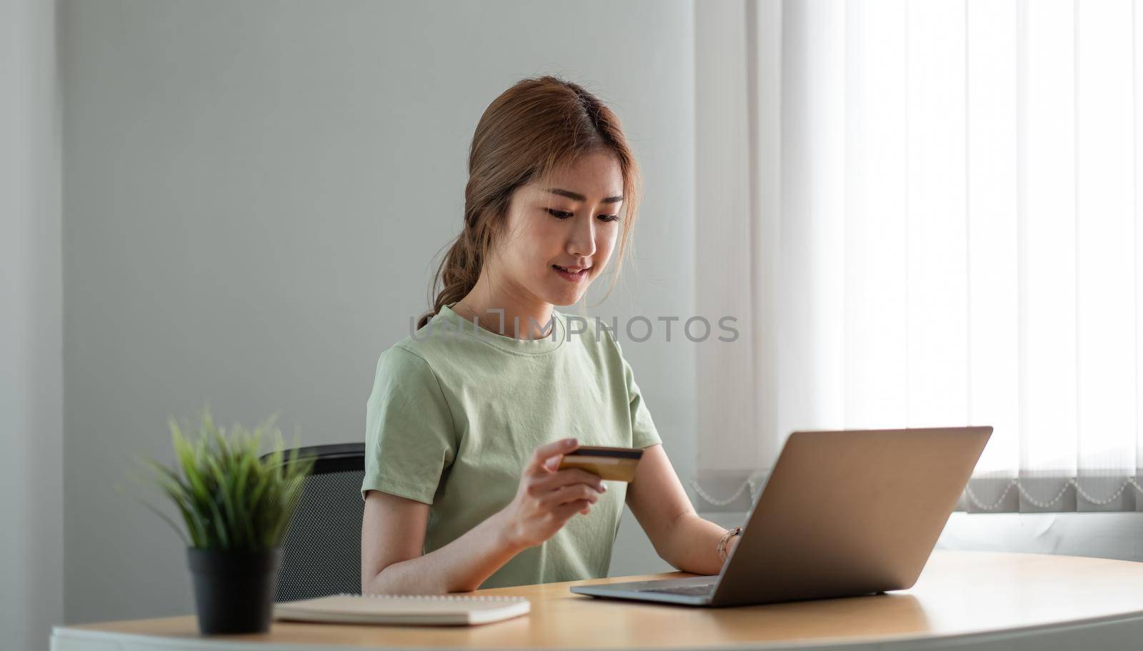 Happy woman doing online shopping at home, woman hand holding credit card and using laptop computer.