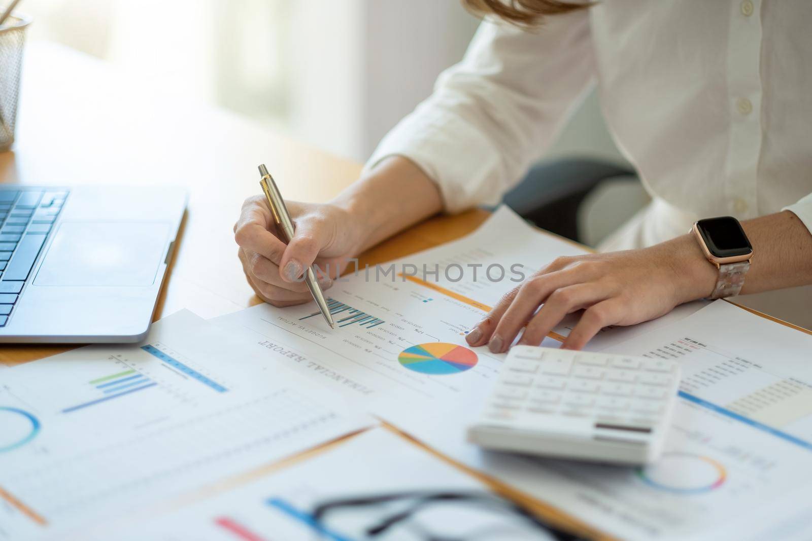 Businesswoman or accountant working on calculator to calculate business data concept. Accounting,investment advisor consulting situation on the financial report and planning a marketing plan at office by nateemee
