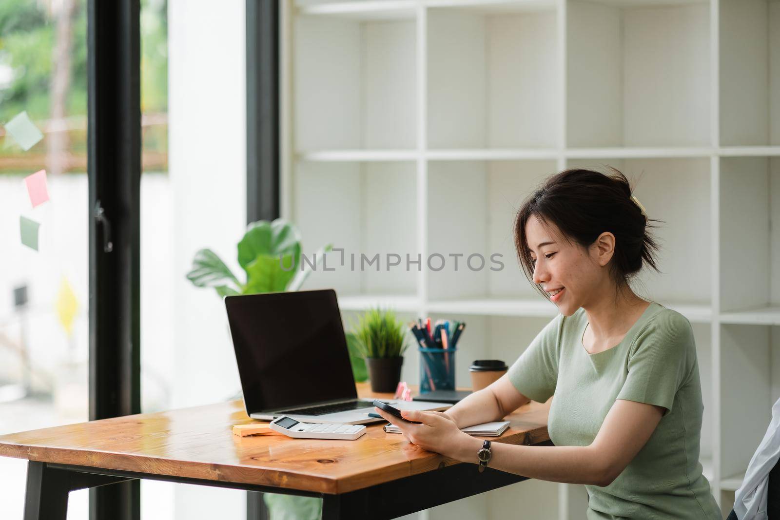 Happy asian woman using mobile phone at modern office,