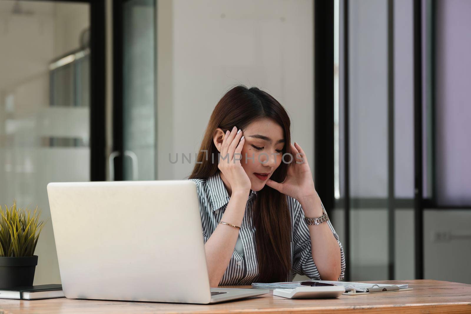 Stressed young woman sitting at desk working from home office, businesswoman headache while having a problem at work in office by nateemee