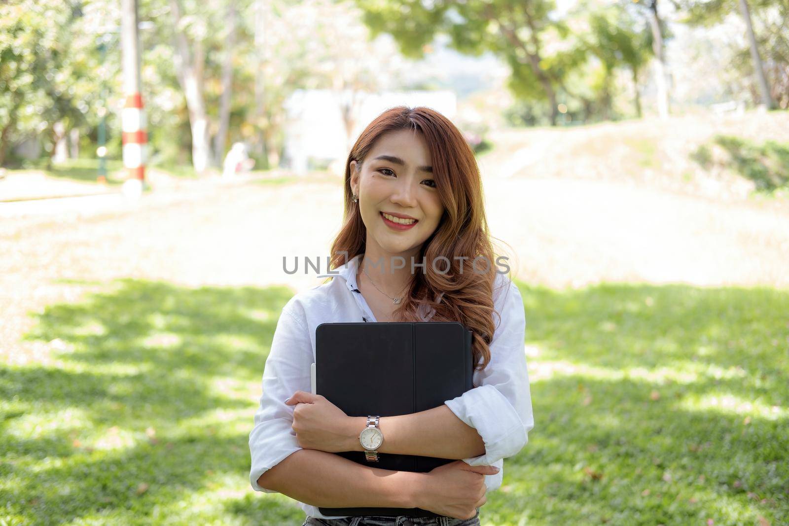 Portrait asian woman university holding digital tablet at the park in a campus, Education concept by nateemee
