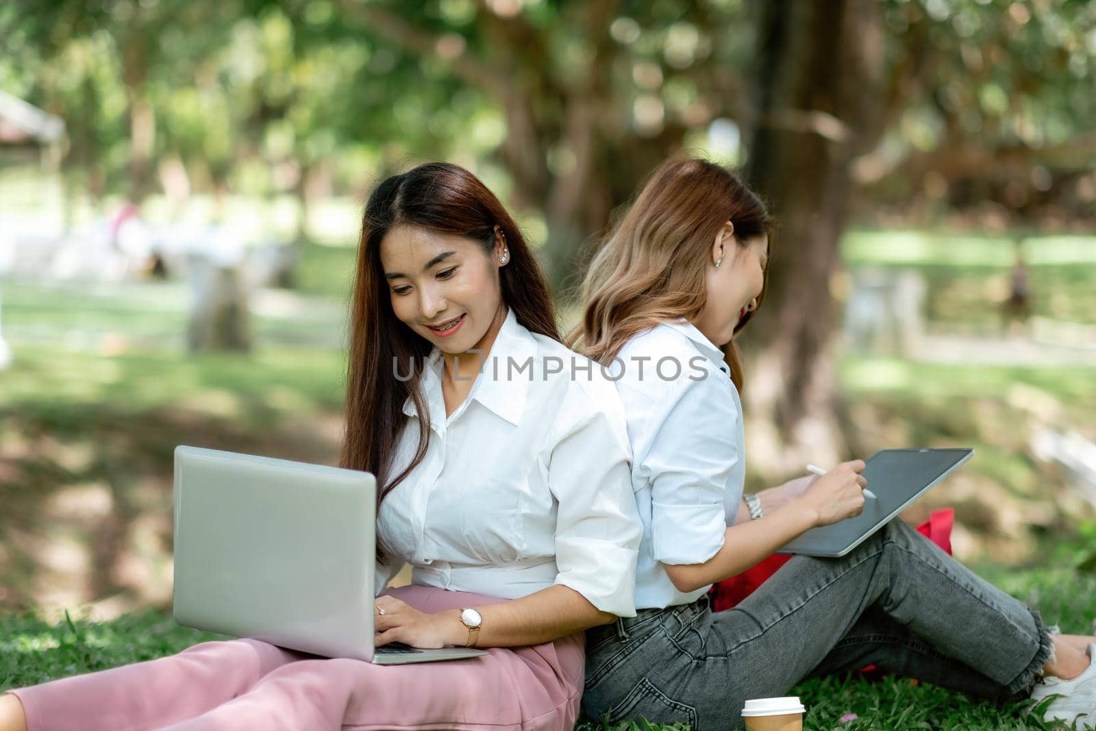 Woman students studying in a group project in the park of university or school. Happy learning, community teamwork and youth friendship concept.