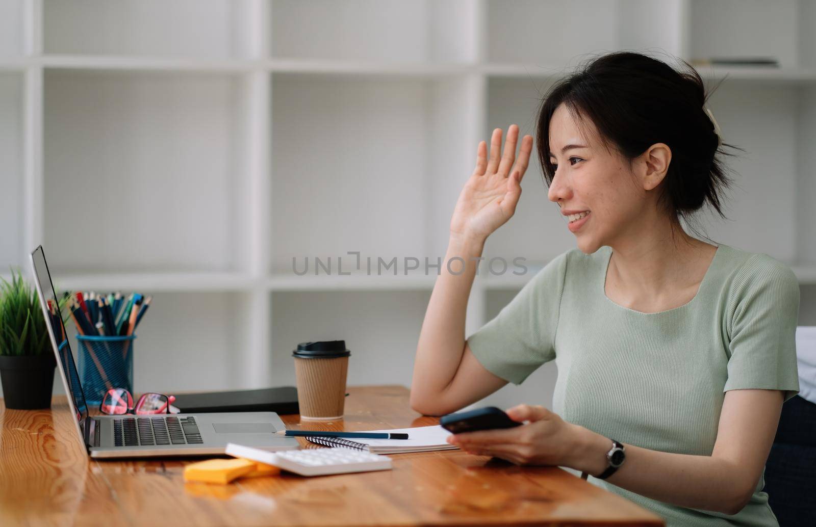Charming asian woman make a video call. business accounting using laptop and calaulator for financing, tax.