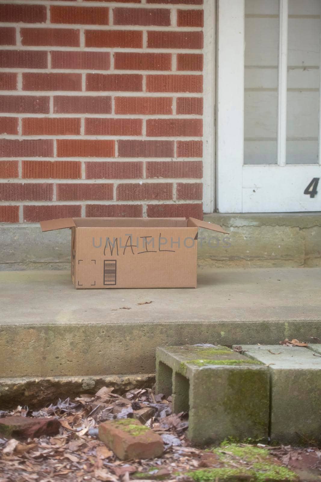 Cardboard box with the word MAIL written on it on a porch