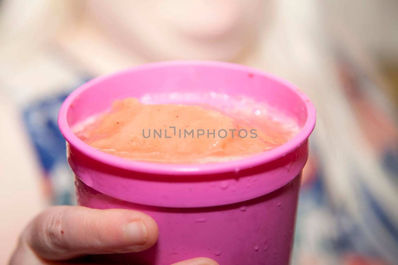 Woman holding a pink cup filled with a pink icy drink