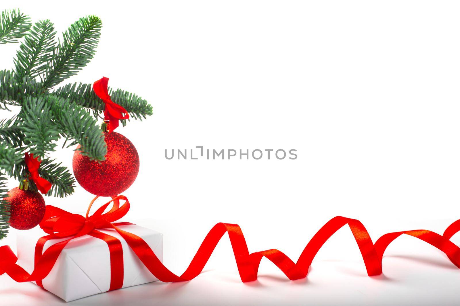 White holiday present gift box with red satin bow and curly ribbon under Christmas tree with baubles, border frame design isolated on white background