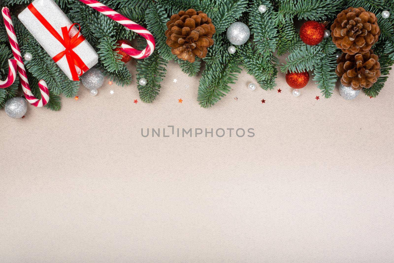 Christmas noble fir tree twigs gift and decorations on brown paper background with copy space for text