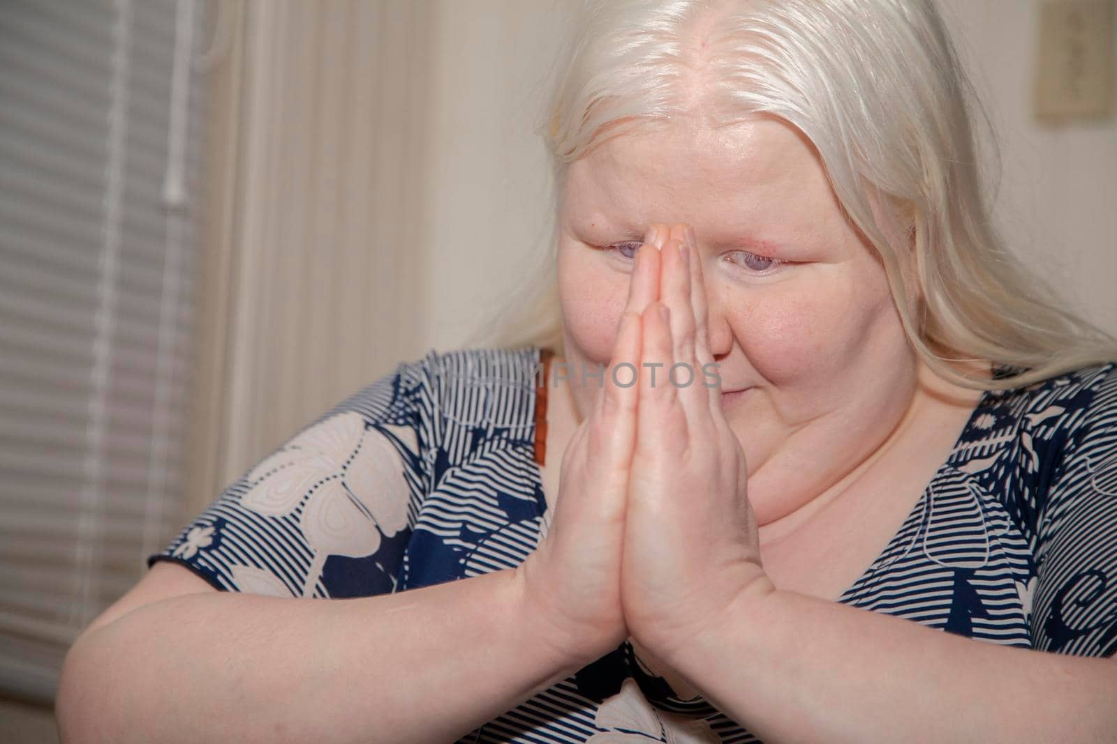 Albino woman praying happily near a door inside