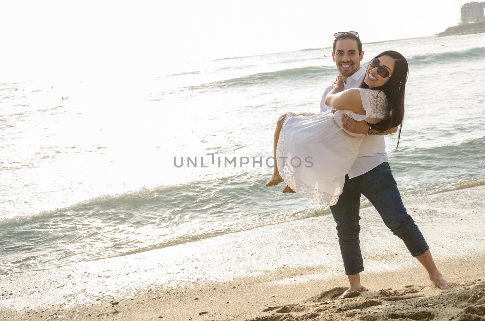 Young man carrying his girlfriend in his arms at the beach