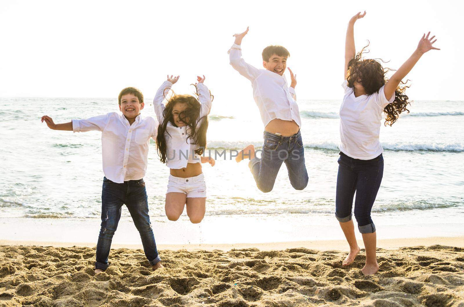 Happy kids jumping together with sunlight on the beach