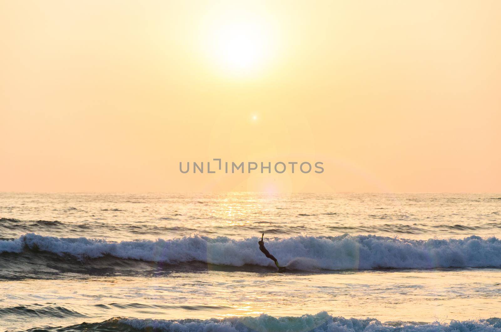 Surfing at Sunset. Young Man Riding Wave at Sunset. Outdoor Active Lifestyle.